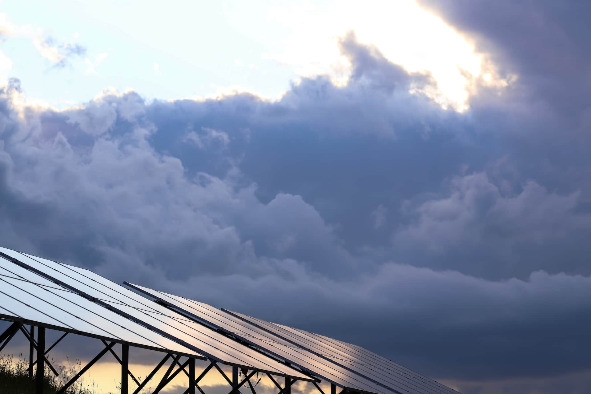 Dark stormy clouds in background looming over solar array wondering should i turn off my solar in a cyclone